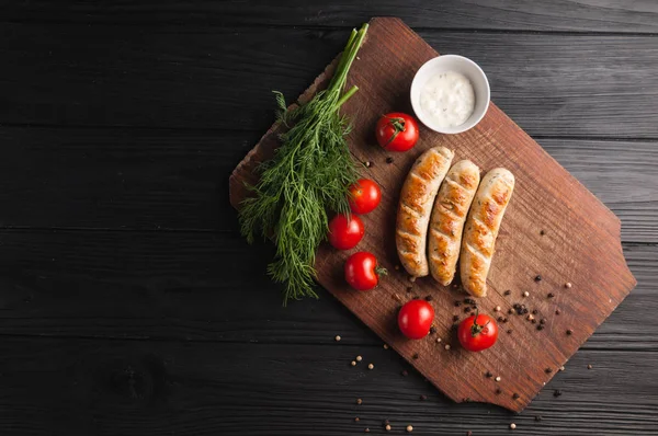 Gegrilde worstjes geroosterd op een bruin houten bord op een houten bac — Stockfoto