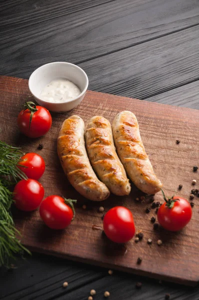 Grilled sausages grilled on a brown wooden board on a wooden bac