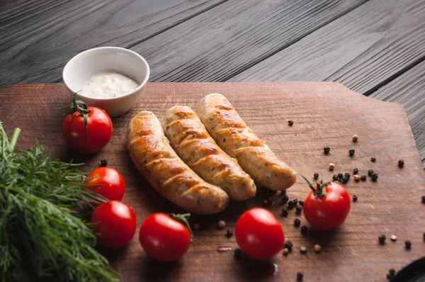 Grilled sausages grilled on a brown wooden board on a wooden bac