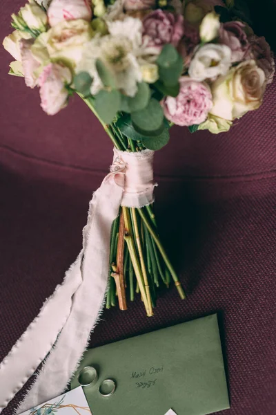 Bruid 's bruiloft boeket in roze stijl, het boeket is gebonden met een roze lint, ernaast zijn uitnodigingen en trouwringen — Stockfoto