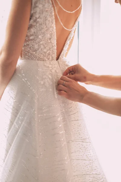 Bridesmaid makes bow-knot on the back of brides wedding dress