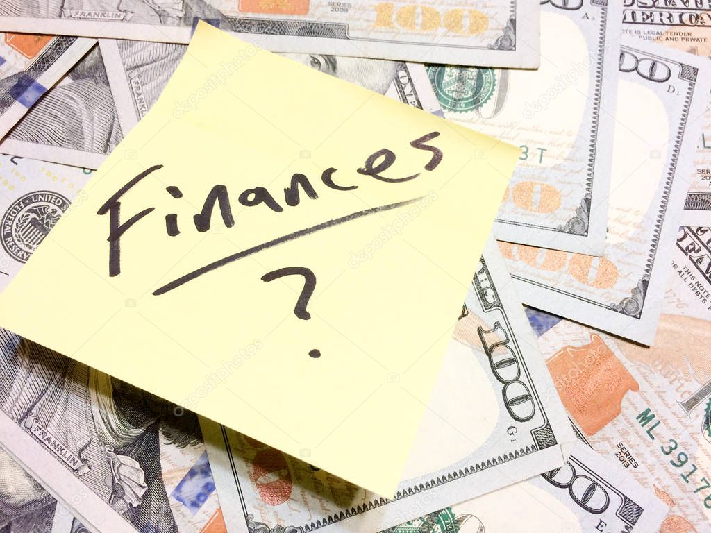 American cash money and yellow sticky note with text Finances with question mark