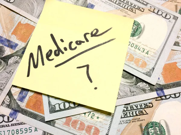 Американские наличные деньги и желтая купюра с текстом Medicare с вопросительным знаком — стоковое фото