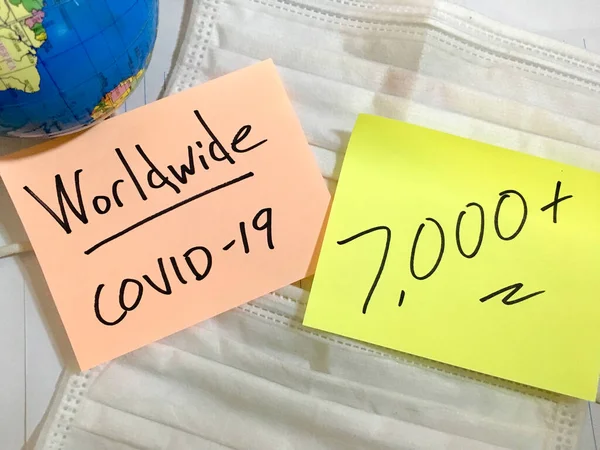 Coronavirus COVID-19 Casos médicos de infección mundial y muertes. China COVID enfermedades respiratorias influenza virus estadísticas mano escrita en máscara quirúrgica y globo terráqueo fondo — Foto de Stock