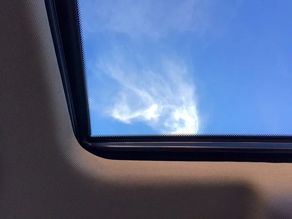 Blauer Himmel mit weißen Wolken durch Autoschiebedach — Stockfoto