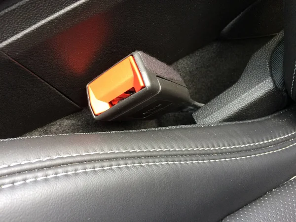 Cierre del cinturón de seguridad en coche de plástico naranja negro cerca del asiento de cuero cosido —  Fotos de Stock