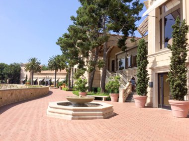 Pahalı bir tatil köyü, yeşil çimenler ve deniz kenarında ağaçlar.