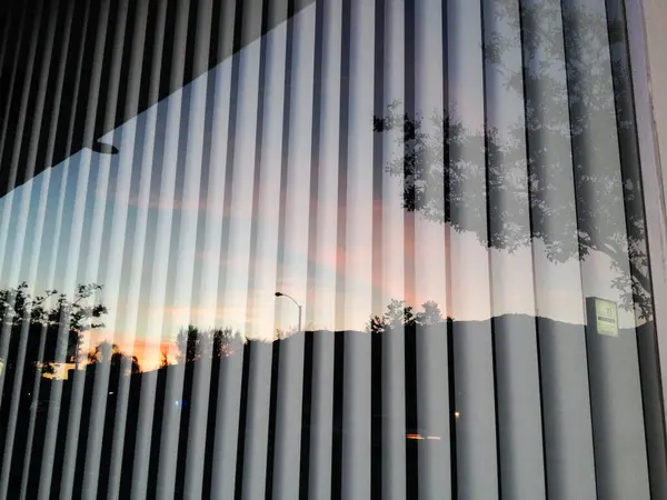 Reflejo de ventana de cristal de puesta de sol con persianas verticales — Foto de Stock