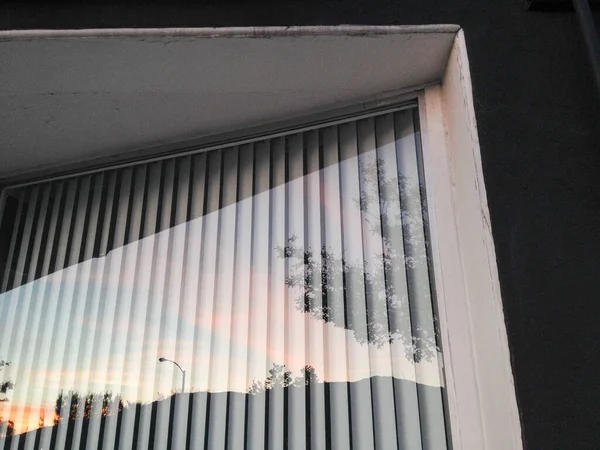 Reflejo de ventana de cristal de puesta de sol con persianas verticales — Foto de Stock