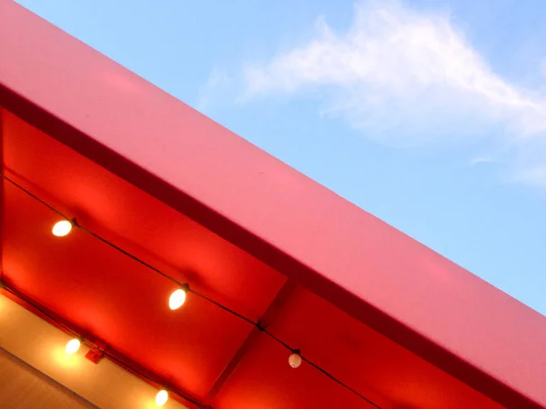 Sarı ampullü kırmızı tente. Mavi gökyüzü ile soyut arkaplan. — Stok fotoğraf
