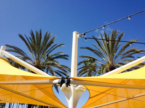 Canopées d'ombre jaune et palmiers par une journée ensoleillée — Photo
