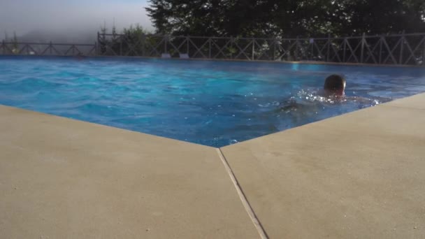 Hombre nadando en una piscina caliente en una mañana brumosa — Vídeo de stock
