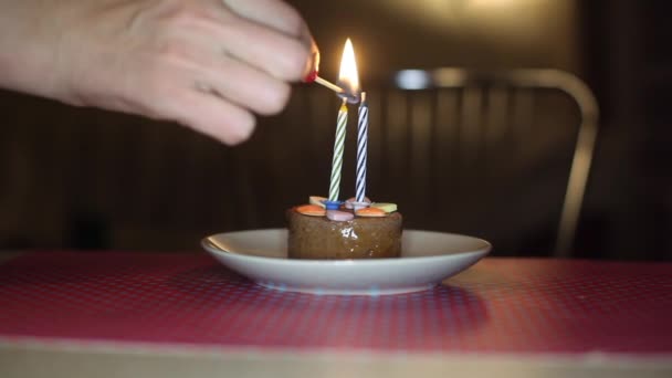 Hand zündet Kerze in der Torte an — Stockvideo