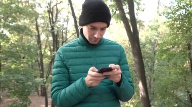 Yakışıklı adam parkta telefonda mesaj yazma
