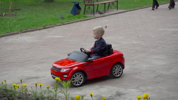 Αγόρι Καβάλα ένα παιχνίδι αυτοκίνητο σε ένα πάρκο — Αρχείο Βίντεο
