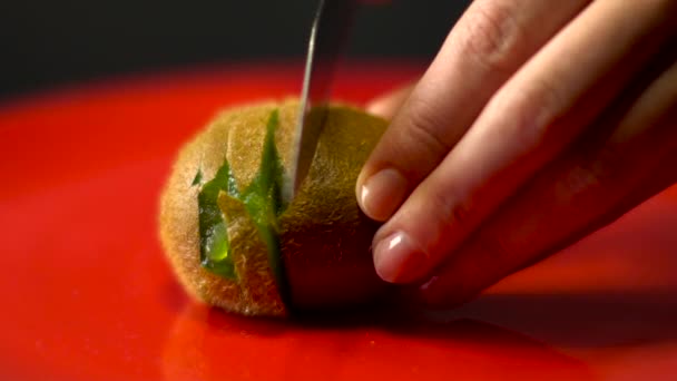 Hand schneidet eine Kiwi mit einem Messer, Nahaufnahme, — Stockvideo
