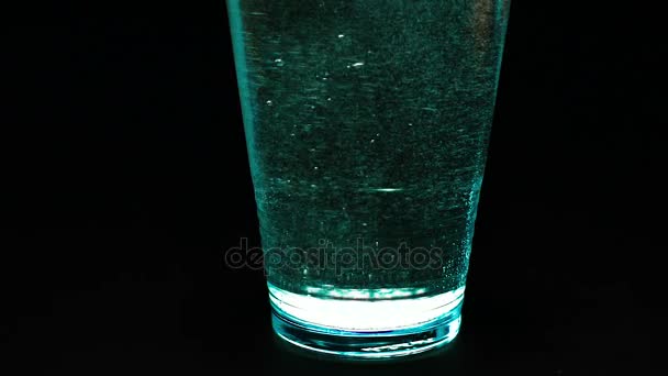 Água mineral em um copo em um fundo preto — Vídeo de Stock