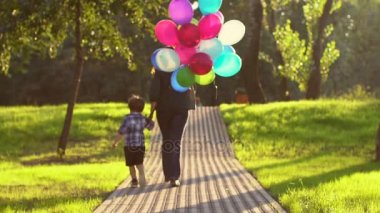 Kız bir çocukla onu balon ile yürüyor