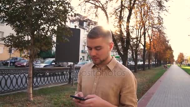 Menino andando na rua e usando o celular — Vídeo de Stock