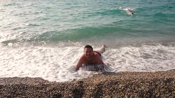 Чоловік лежить на пляжі розслабляючий — стокове відео