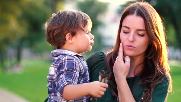 Son kisses mother on the cheek in the park at sunset Mother and her little son outdoors, Happy family mom and kid kissing and hugging. Slow motion, high speed camera shot. Full HD 1080p — Stock Video