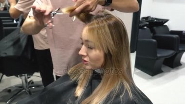 Genç kadın kesme beyaz arka plan üzerinde izole Kuaför saçlara. Kuaför Saç bir genç kız için profesyonel bir makas ile keser.