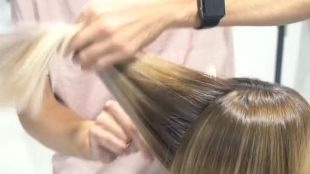 Le coiffeur coupe la fille. Fait une coiffure pour une femme. Gros plan sur la coupe de cheveux. Ciseaux et peigne chez le styliste. Beaux cheveux d'une jeune femme. 4k — Video