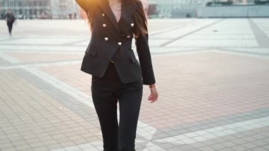 Genç yetişkin iş kadını şehirde yürüyor.