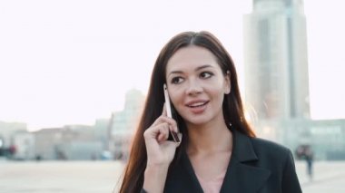 Genç yetişkin iş kadını şehirde modern akıllı telefondan konuşuyor.