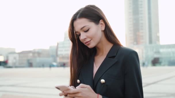 Joven mujer de negocios adulta usando un teléfono inteligente moderno en la ciudad — Vídeos de Stock