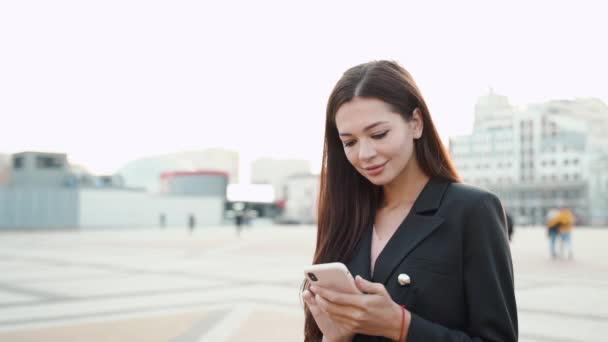 Joven mujer de negocios adulta sonriendo, usando un teléfono inteligente moderno — Vídeos de Stock