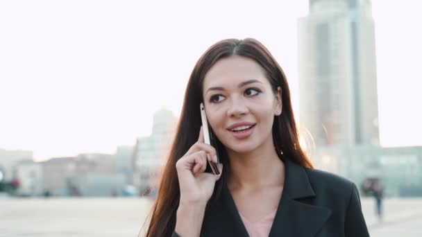 Junge erwachsene Geschäftsfrau spricht auf modernem Smartphone in der Stadt — Stockvideo