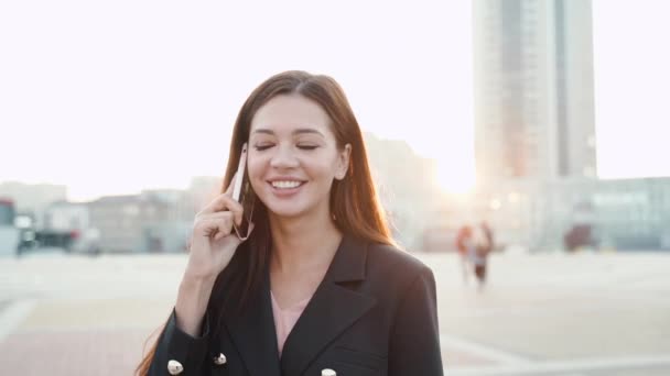 Jovem empresária adulta sorrindo e conversando no smartphone moderno — Vídeo de Stock