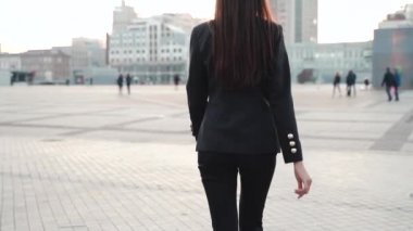 Sokakta yürüyen takım elbiseli genç bir iş kadını.