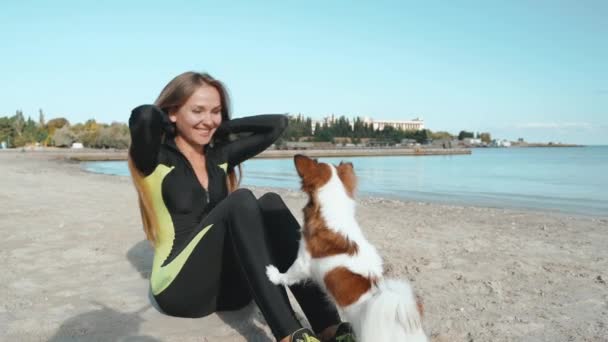 年轻的成年女运动员在海边用狗做运动 — 图库视频影像
