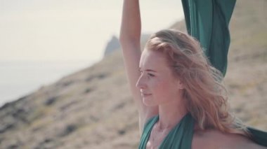 Genç yetişkin bir kız şık yeşil elbisesiyle tepede duruyor.