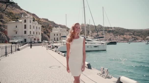 Jovem senhora adulta em vestido branco casual andando perto do mar — Vídeo de Stock