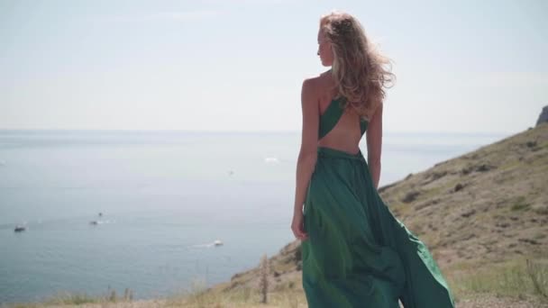 Młoda dorosła kobieta stojąca na wzgórzu w modnej zielonej sukience — Wideo stockowe