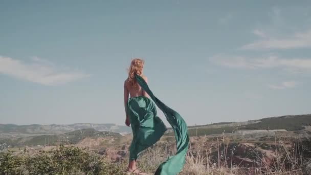 Joven chica adulta de pie al aire libre en elegante vestido verde — Vídeo de stock