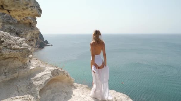 Молодая женщина смотрит на море, стоя спиной к камере — стоковое видео