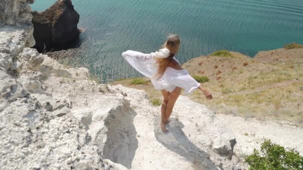 Giovane donna adulta in piedi sulla roccia e guardando il mare — Video Stock