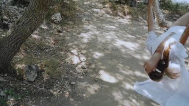 Genç yetişkin kız salıncakta oturuyor, poz veriyor ve eğleniyor.