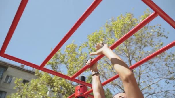 Young adult sporty girl training outdoors, intercepts the bars — Stockvideo