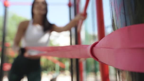 Young adult sporty woman training outdoors using rubber elastic tape — 비디오