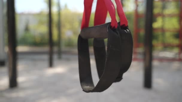 Close up of pair with black loops strip equipment hanging outdoors — 图库视频影像