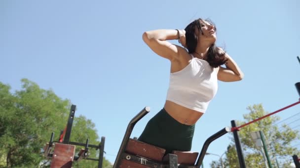 Молодой спортсмен девушка тренировки на открытом воздухе делает пресс и обратно тренировки — стоковое видео