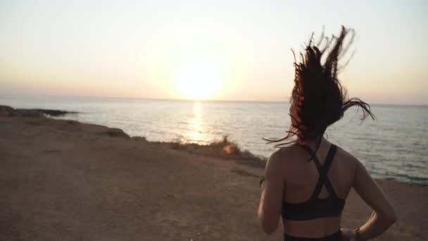 Jovem mulher esportiva adulta treinando ao ar livre correndo na praia perto do mar — Vídeo de Stock