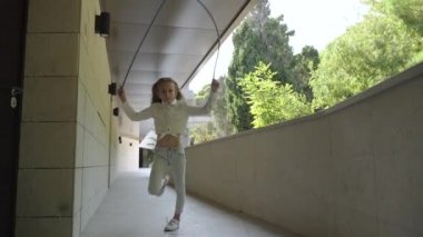 Junior girl jumping up, holding rope in hands