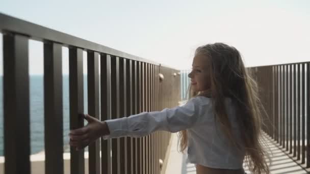 Child girl walking outside, touching metal fence and smiling wide — 图库视频影像