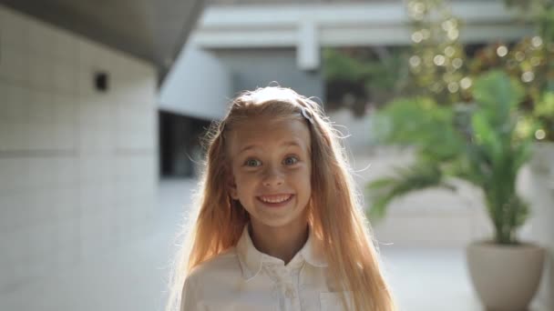 Gyermek lány, hogy vicces arc, szemben áll az építészet háttér — Stock videók